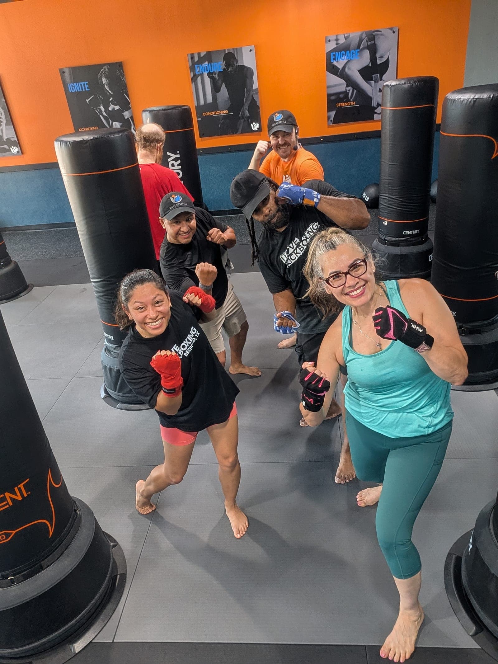 A small beginner kickboxing class at Vibes Lifestyle, with a mixed group of first-timers and a coach, smiling with fists up